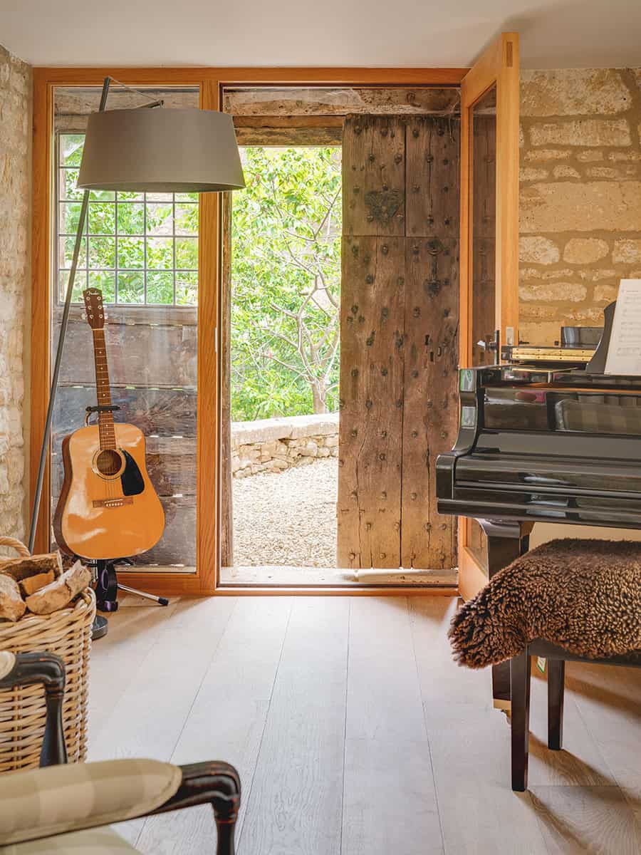 The Mount, an oak-framed glazed doorway beside an old studded timber door, with a piano and stone walls